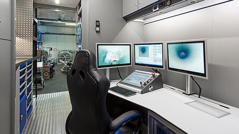 Three screens with a control panel to monitor the milling process in a pipe system