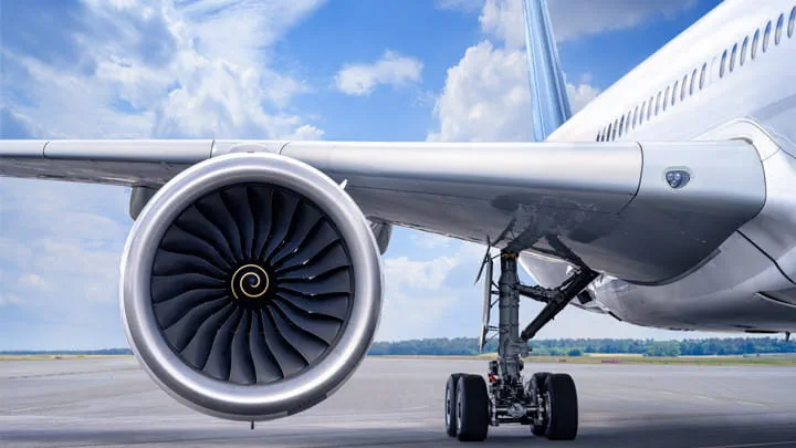 Close-up view of an aircraft engine and landing gear on the runway under a clear sky