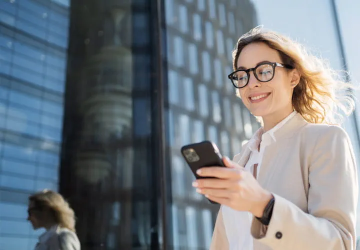 Person som använder en smartphone framför en modern glasbyggnad
